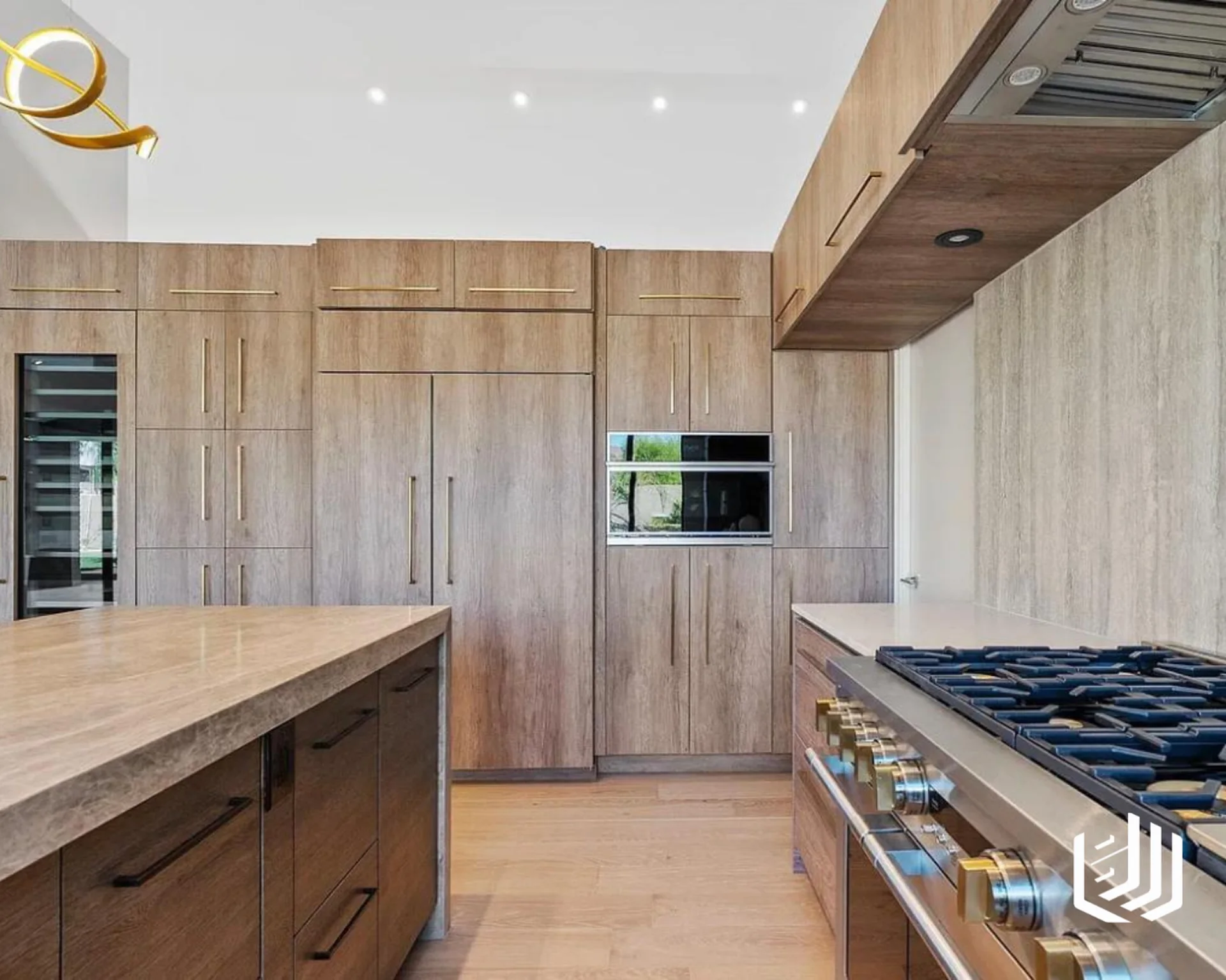 Tall wood kitchen cabinets with integrated appliances beside a stone island