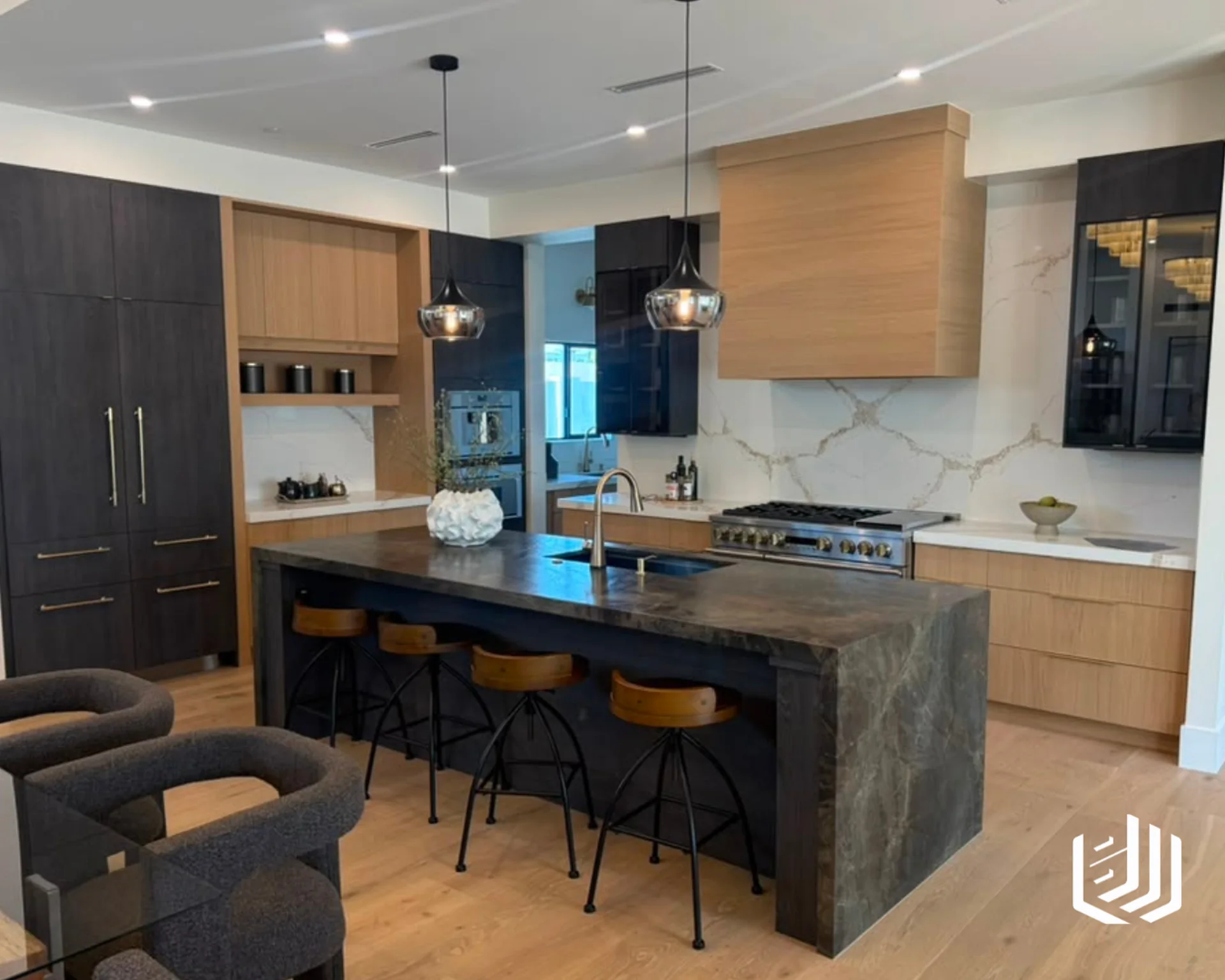 Dark waterfall kitchen island with four stools and mixed dark and light wood cabinets