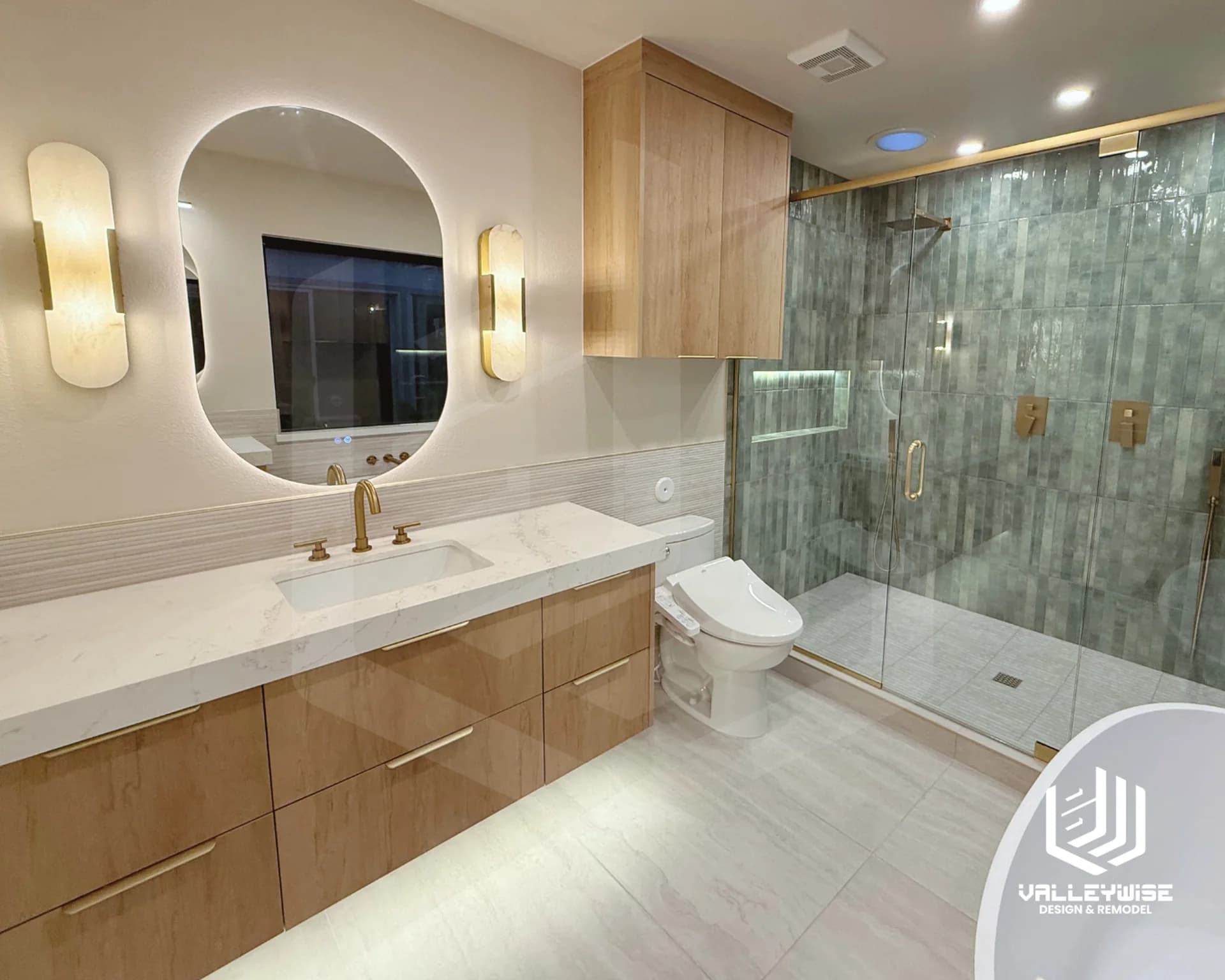 Bathroom with a wood vanity, green tiled shower and gold fixtures